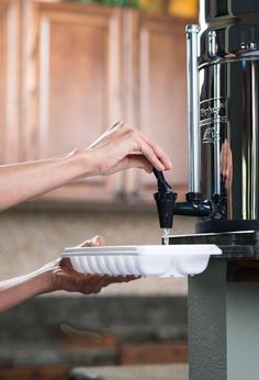 a person is filling up a container with water from a faucet in a kitchen