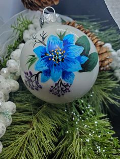 a blue flower ornament sitting on top of a christmas tree next to pine cones