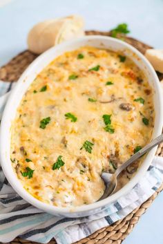 a close up of a casserole in a bowl on a table with bread