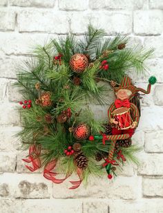 a christmas wreath on a brick wall with pine cones and red ribbon around the wreath