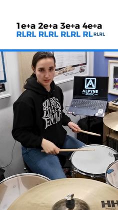 a woman sitting in front of a laptop computer with a drum set on her lap