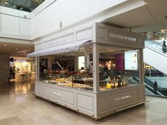 the inside of a store with people walking around and food on display behind glass cases