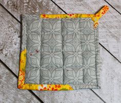 a quilted placemat on a wooden floor with yellow and orange trim around the edges