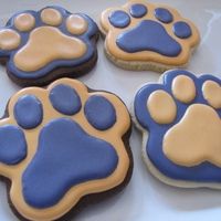 four decorated cookies with blue and brown paw prints