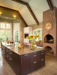 a large kitchen with an island in front of a brick oven and table surrounded by chairs