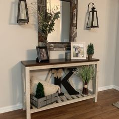 an entryway with a bench, mirror and potted plants on the sideboard