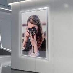 a woman holding a camera in front of her face and taking a photo with it