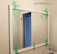 a mirror that has been painted with green tape on the frame and is in front of a sink