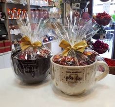 two coffee mugs filled with candy wrapped in cellophane