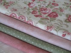 four different colored fabrics are stacked on top of each other, one is pink and the other is green