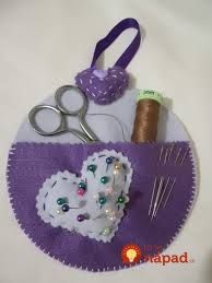 scissors, thread, and other crafting supplies are arranged in a purple holder on a white surface