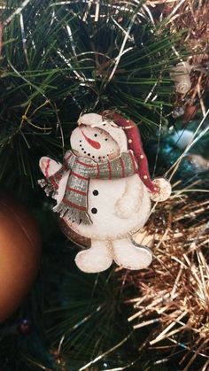 a snowman ornament hanging from a christmas tree