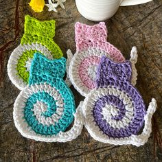 three crocheted coasters sitting on top of a table next to a cup