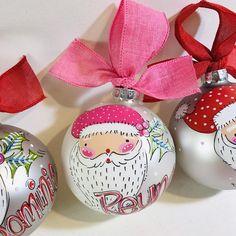 three christmas ornaments with pink bows and santa's face on one ornament