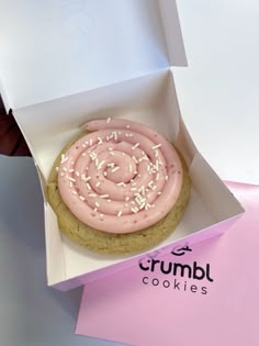 a pink frosted cookie in a white box