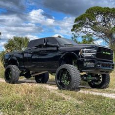 a large black truck parked on top of a dirt road