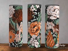 three floral vases sitting on top of a wooden table