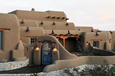 an adobe - style house with birds perched on it's roof and door, in the desert