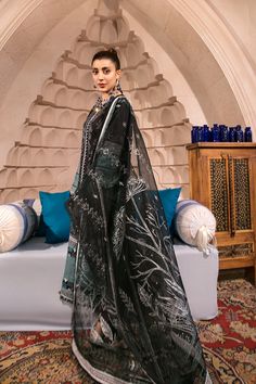 a woman standing in front of a bed wearing a black and white sari dress