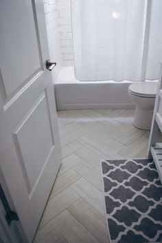 a bathroom with a toilet, bathtub and rug