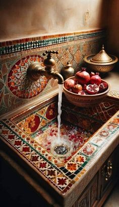 a bowl of pomegranates sits on top of a sink with water running from the faucet