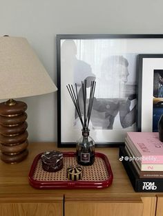 a wooden dresser topped with books and a lamp next to a framed photograph on top of it