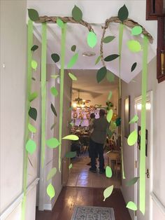 a man is walking down the hallway in front of a door decorated with green leaves