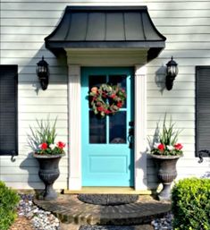 a blue front door with two planters on either side