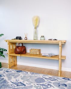 a wooden shelf with a handbag and purse on it next to a blue rug