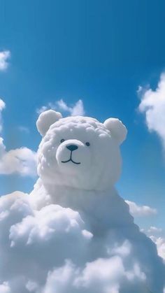 a white teddy bear sitting on top of a cloud in the sky with clouds around it