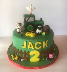 a green birthday cake with farm animals on top and the number two written in white