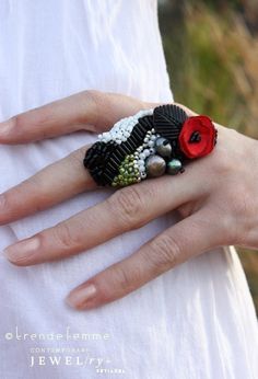 a woman's hand with a ring made out of beads and flowers on it