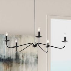 a black chandelier with five lights hanging from it's center and an abstract painting on the wall behind it