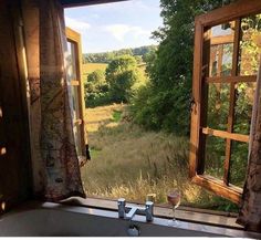 a bath tub sitting in front of a window next to a lush green forest filled with trees