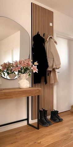 there is a coat rack with shoes and flowers on it in the corner next to a mirror