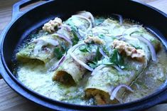 some food is in a black pan on a wooden table and ready to be eaten