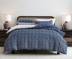 a bed with blue and white comforter in a bedroom next to two lamps on nightstands