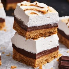 three pieces of cake sitting on top of each other next to some chocolate and marshmallows