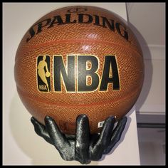 a close up of a basketball on a white wall with black hands holding the ball