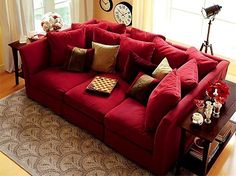 a large red couch sitting on top of a living room floor next to a window