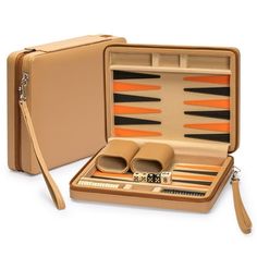 an open leather backgamzer set with orange and black pieces in the case on a white background