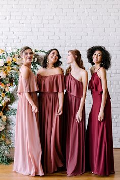 three women in long dresses standing next to each other and smiling at the same time