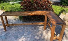 a wooden bench sitting next to a bush