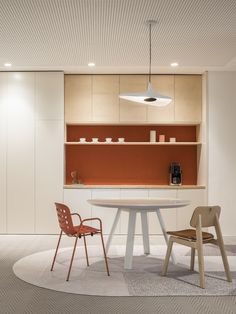 two chairs and a table in a room with white flooring, an orange wall