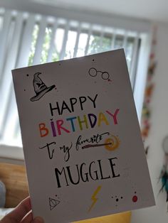 a hand holding up a birthday card that says happy birthday to my favorite muggle