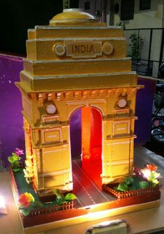 a small model of the india gate is lit up in red and yellow lights at night