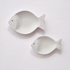 two white fish shaped dishes sitting on top of each other