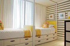 a bedroom with yellow and white striped walls, drawers and a bed in the middle