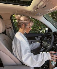 a woman sitting in the driver's seat of a car