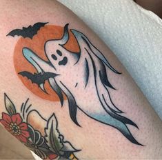 a woman's arm with a ghost and flowers tattoo design on the left thigh